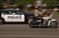 Police motorcycle and car driving side by side.